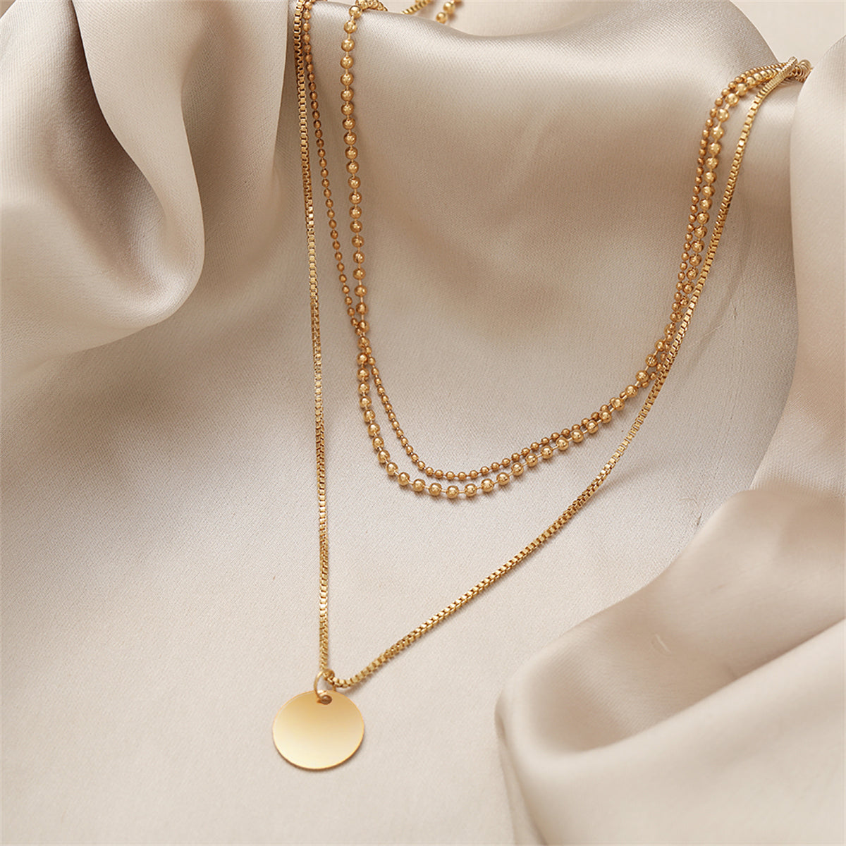 Fashionable 18K gold-plated necklace with a layered design, featuring a disc and two chains for a sophisticated touch.