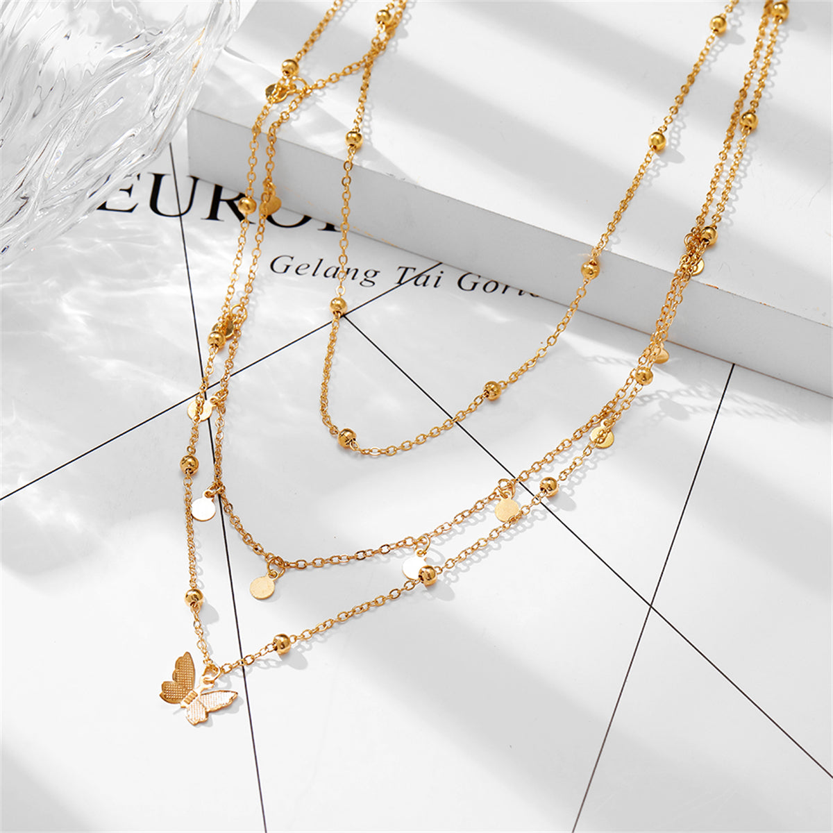 Dazzling 18K gold-plated butterfly necklace showcasing three layers of gold beads, ideal for elevating your outfit.