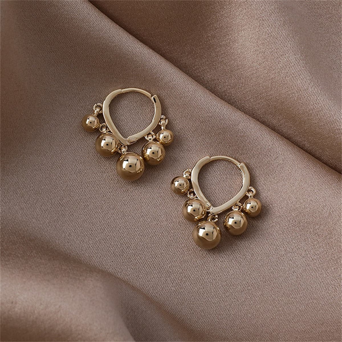 Beautiful 18K gold-plated huggie earrings with playful ball tassels, perfect for making a fashionable statement.
