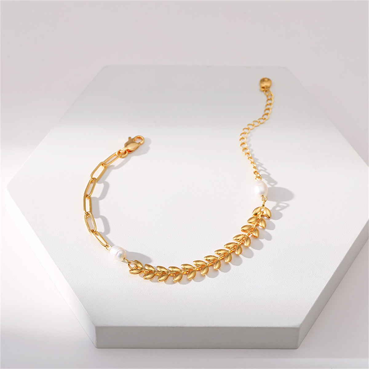 A stylish gold bracelet with a leaf charm and pearl beads, crafted from an 18K gold-plated wheat chain for a luxurious look.