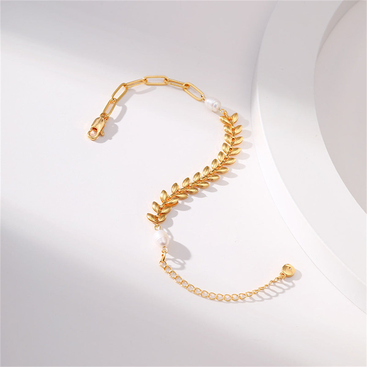 A sophisticated gold bracelet with a leaf charm and pearl beads, featuring a delicate 18K gold-plated wheat chain design.