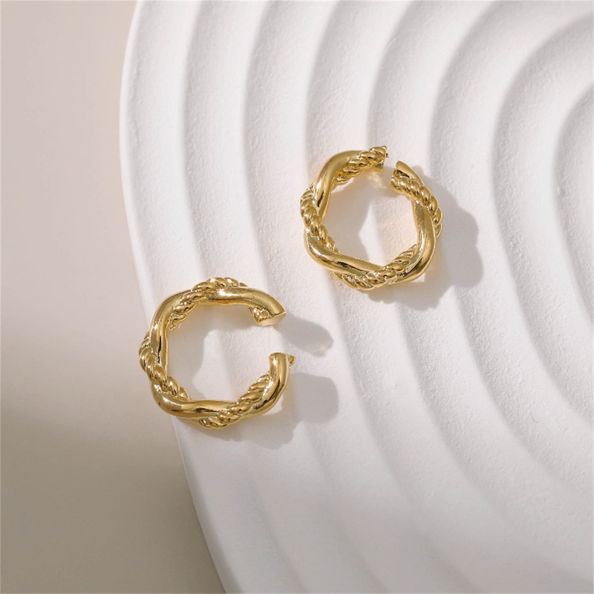 Chic gold-tone hoop earrings with a twisted rope texture, made from 18K gold plating, perfect for any fashion-forward wardrobe.