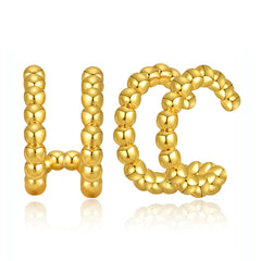 A stunning gold letter 'H' adorned with a vibrant ball of beads, showcasing 18K gold-plated layered ear cuffs.