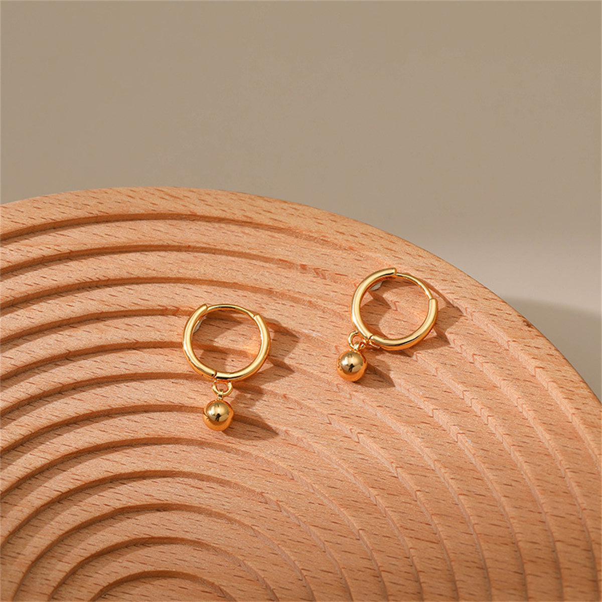 Dazzling 18K gold-plated hoop earrings showcasing a unique ball element, perfect for making a statement.