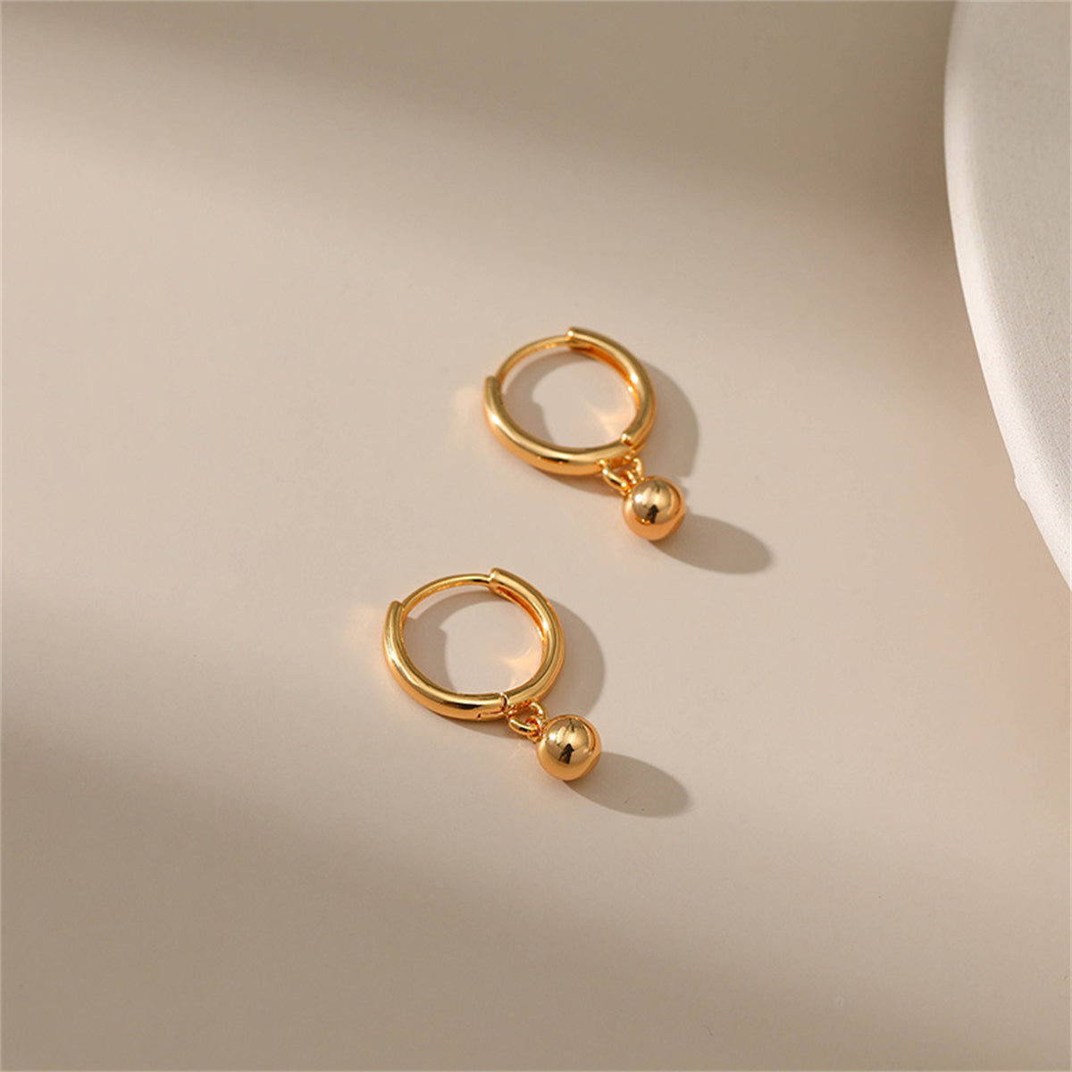 Stunning 18K gold-plated hoop earrings with a chic ball accent, adding a touch of luxury to your look.