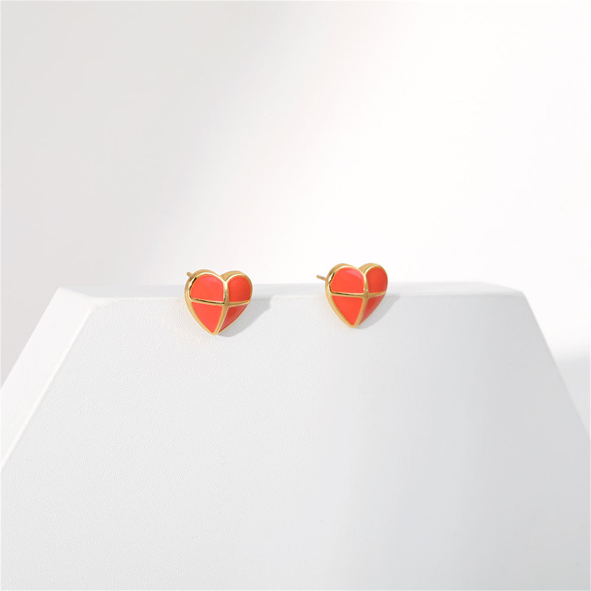 Stylish red heart-shaped stud earrings featuring a red enamel finish and luxurious 18K gold plating.