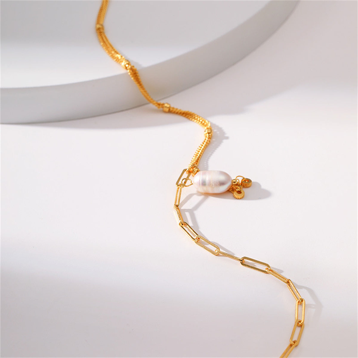 An exquisite multi-chain necklace in 18K gold plating, featuring a prominent pearl pendant for added elegance.