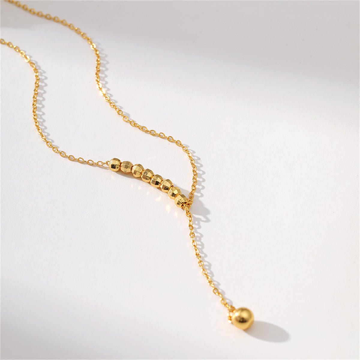 Exquisite 18K gold-plated bead lariat necklace with a shimmering diamond pendant.