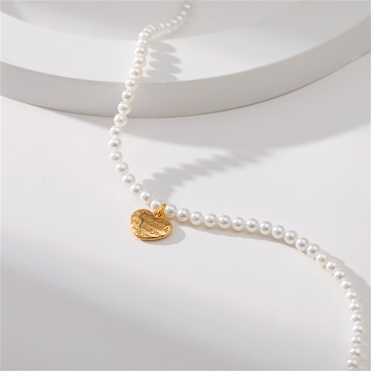 A refined white pearl necklace with a gold heart charm, complemented by an 18K gold-plated 'Love You' heart pendant.