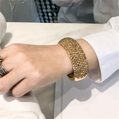 An elegant bangle in gold-tone, embellished with a large cubic zirconia stone, made from 18K gold plating for added glamour.