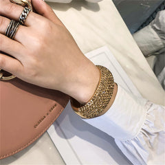 A stunning gold-tone bangle with a large crystal stone, featuring 18K gold plating and cubic zirconia for a chic accessory.