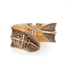 A gold cuff featuring an elegant feather design, crafted in enamel and 18K gold plating, showcasing a bypass style.