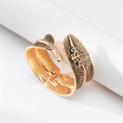 An 18K gold-plated cuff adorned with a delicate feather design, made from enamel, exemplifying a stylish bypass bangle.