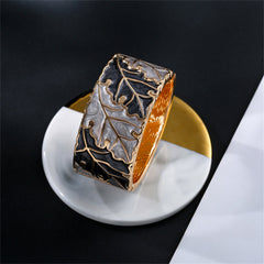 A refined bangle with oak leaf design, embellished with gold and silver accents, featuring gray and black enamel and 18K gold.