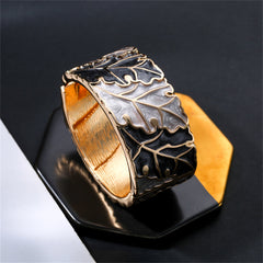 An exquisite oak leaf bangle with gold and silver details, designed with gray and black enamel and plated in 18K gold.