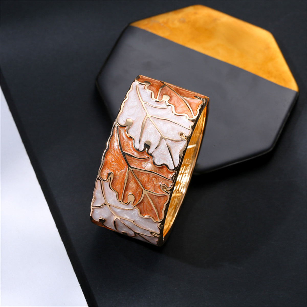 A chic gold and white leaf bangle, beautifully designed with a leaf pattern and enriched with orange enamel and 18K gold plating.