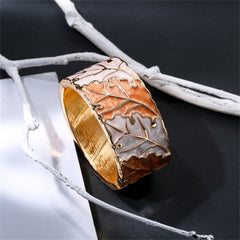 A stylish bangle in gold and white, designed with a leaf pattern, complemented by orange enamel and 18K gold plating.