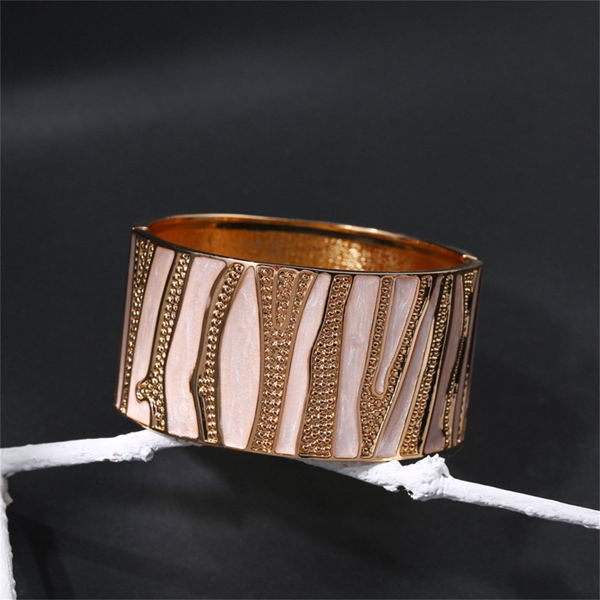A refined bracelet in gold and white, adorned with a branch motif, made from white enamel and 18K gold plating.