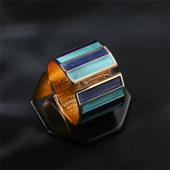 A blue enamel cuff bracelet with gold stripes, showcasing a sophisticated design in 18K gold plating.