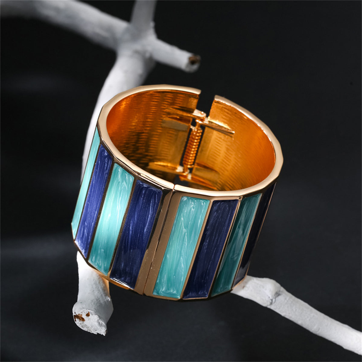 An elegant cuff bracelet in blue and gold, featuring stripes and crafted from blue enamel with 18K gold plating.