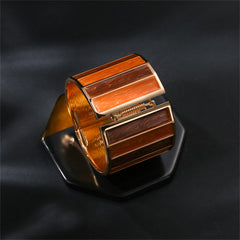Brown and orange striped bangle bracelet made of orange enamel and 18K gold plating, offering a chic accessory option.