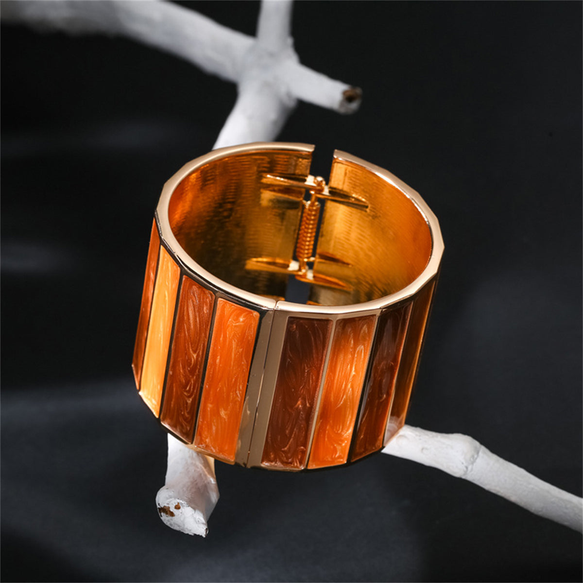 A cuff bracelet featuring brown and orange stripes, designed with orange enamel and 18K gold plating for an elegant look.