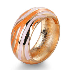 An abstract bangle showcasing a swirl design in gold and orange, made with orange enamel and 18K gold plating.