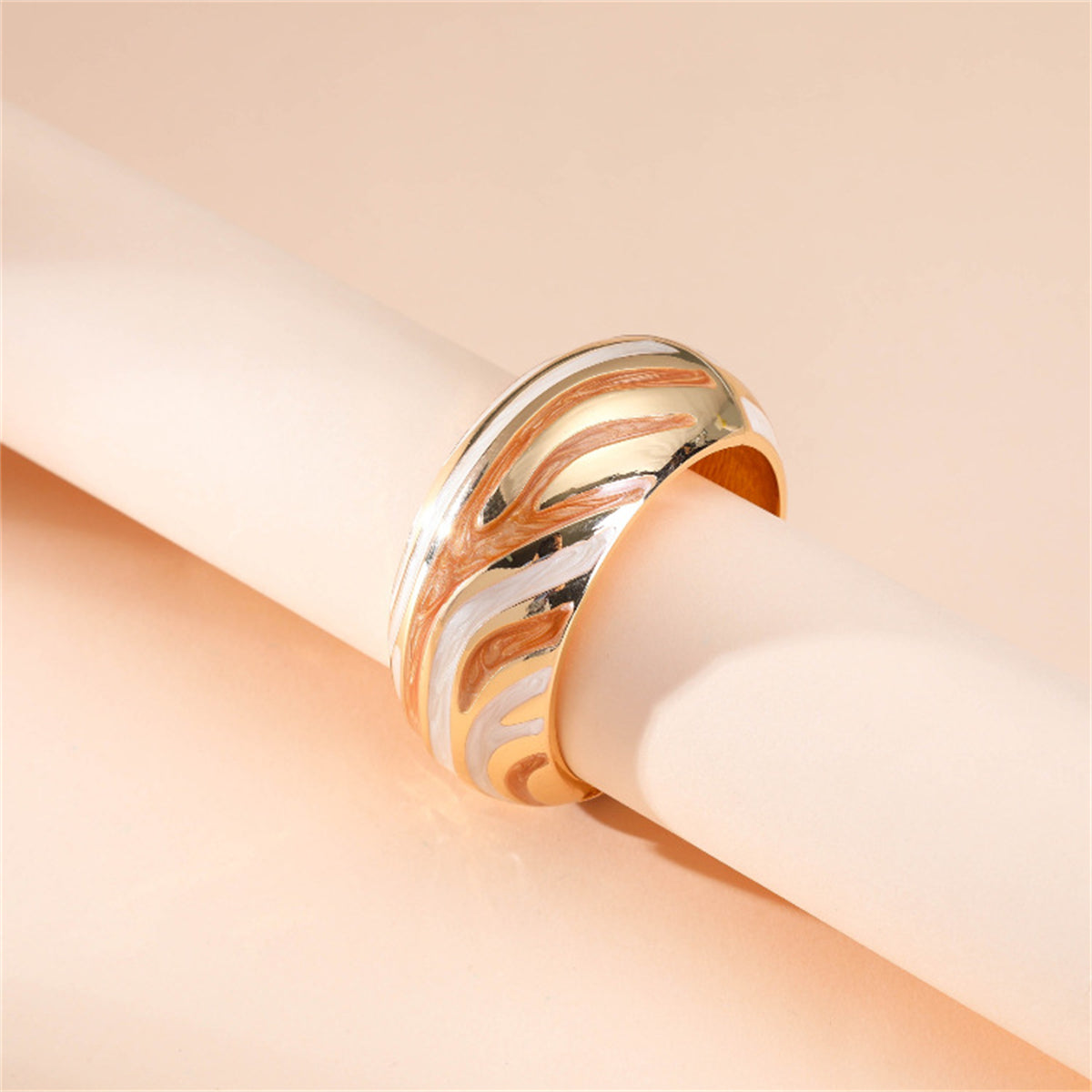 A stylish gold and orange bracelet with a swirling pattern, designed in orange enamel and plated with 18K gold.