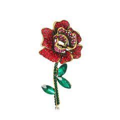 A stunning 18K gold-plated brooch featuring a red rose adorned with red cubic zirconia and green crystals.