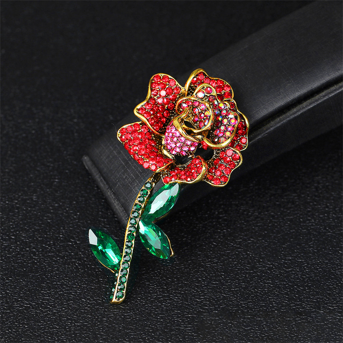 Elegant 18K gold-plated rose brooch embellished with red cubic zirconia and green stones, showcasing exquisite craftsmanship.