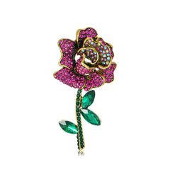 Elegant pink rose brooch with green leaves and pink crystals, crafted in 18K gold plating and cubic zirconia.