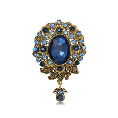 Elegant blue and gold brooch with a prominent oval stone, embellished with cubic zirconia in a floral drop design.