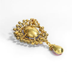 A decorative brooch in green and various colors, designed with a teardrop shape and set with crystals and cubic zirconia.