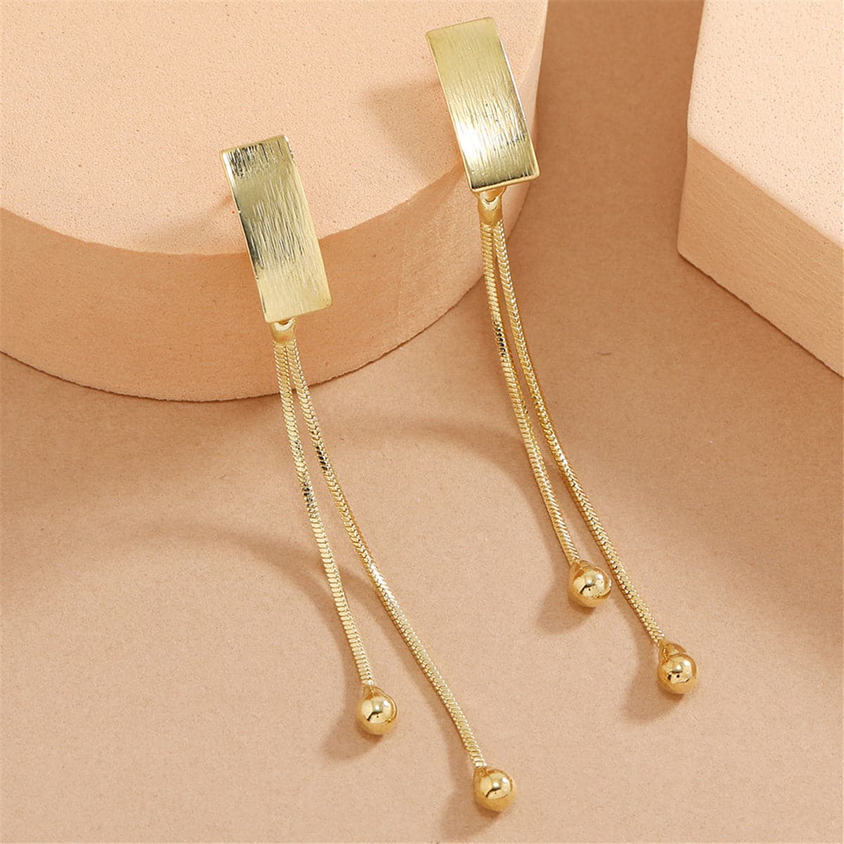 Elegant 18K gold-plated earrings featuring a rectangular bar design with two delicate beaded tassels for a chic look.