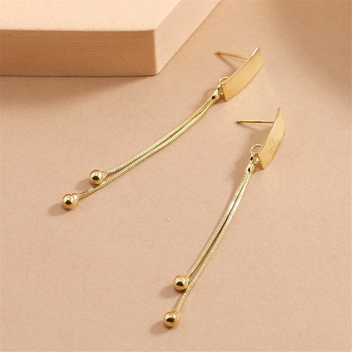 Fashionable 18K gold-plated earrings designed with a rectangular bar and two small balls, adding a touch of elegance.