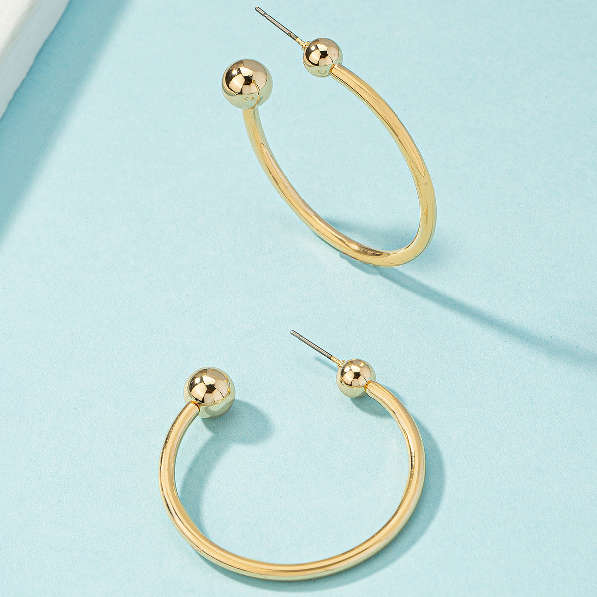 Chic 18K gold-plated ball end huggie earrings, designed to enhance your style with their luxurious gold hoop finish.
