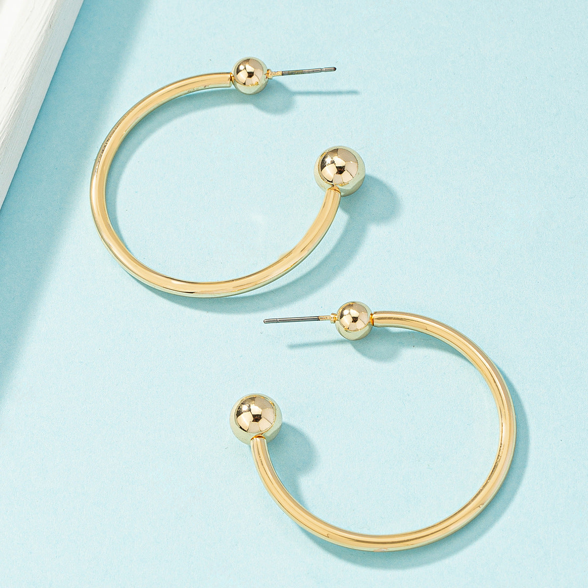 Stylish 18K gold-plated hoop earrings featuring ball ends, ideal for a sophisticated and trendy accessory choice.