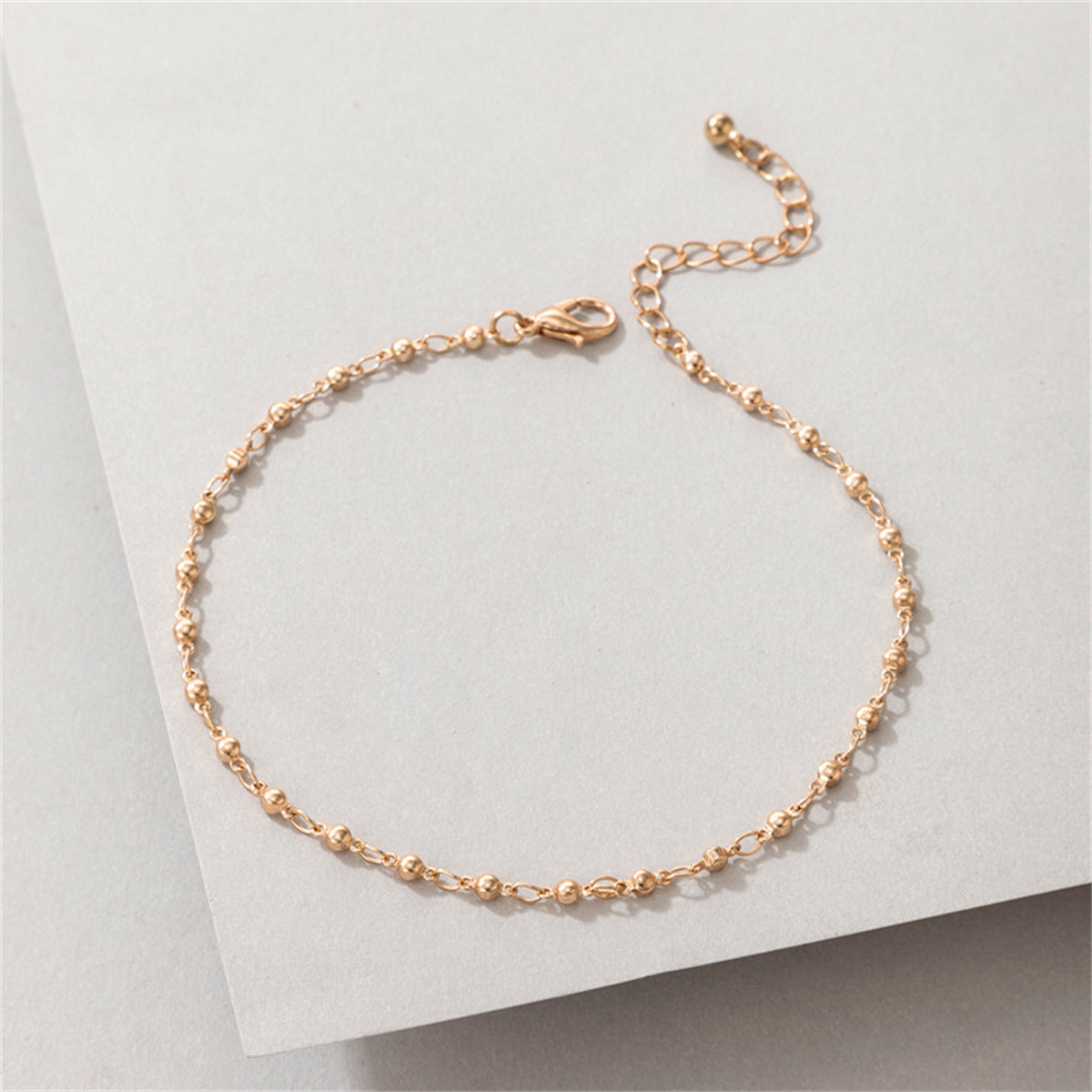 Stunning 18K gold-plated beaded chain anklet resting on a clean white background, highlighting its exquisite design.