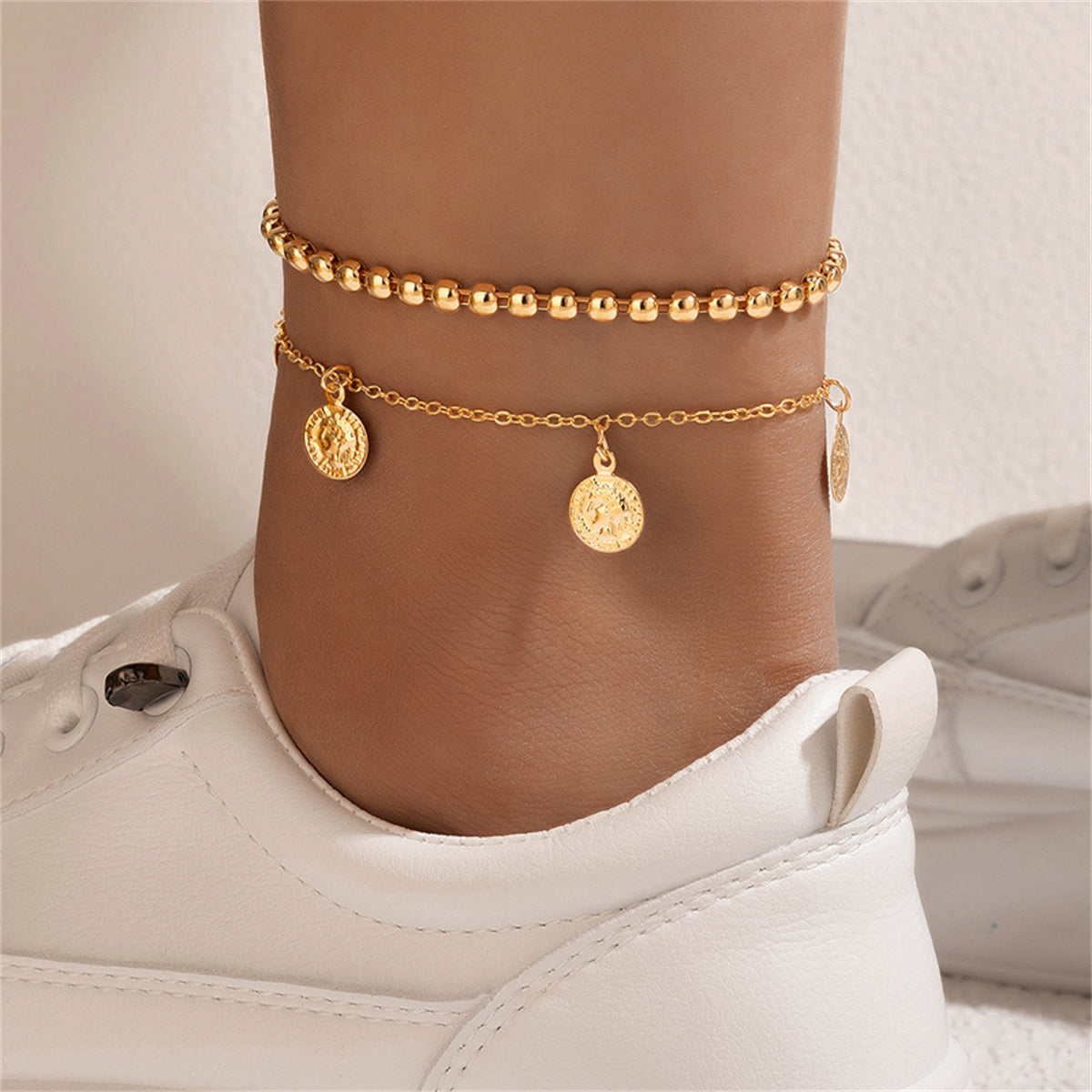 A stunning pair of gold chain anklets with charms, showcasing an exquisite 18K gold-plated coin tassel bead style.