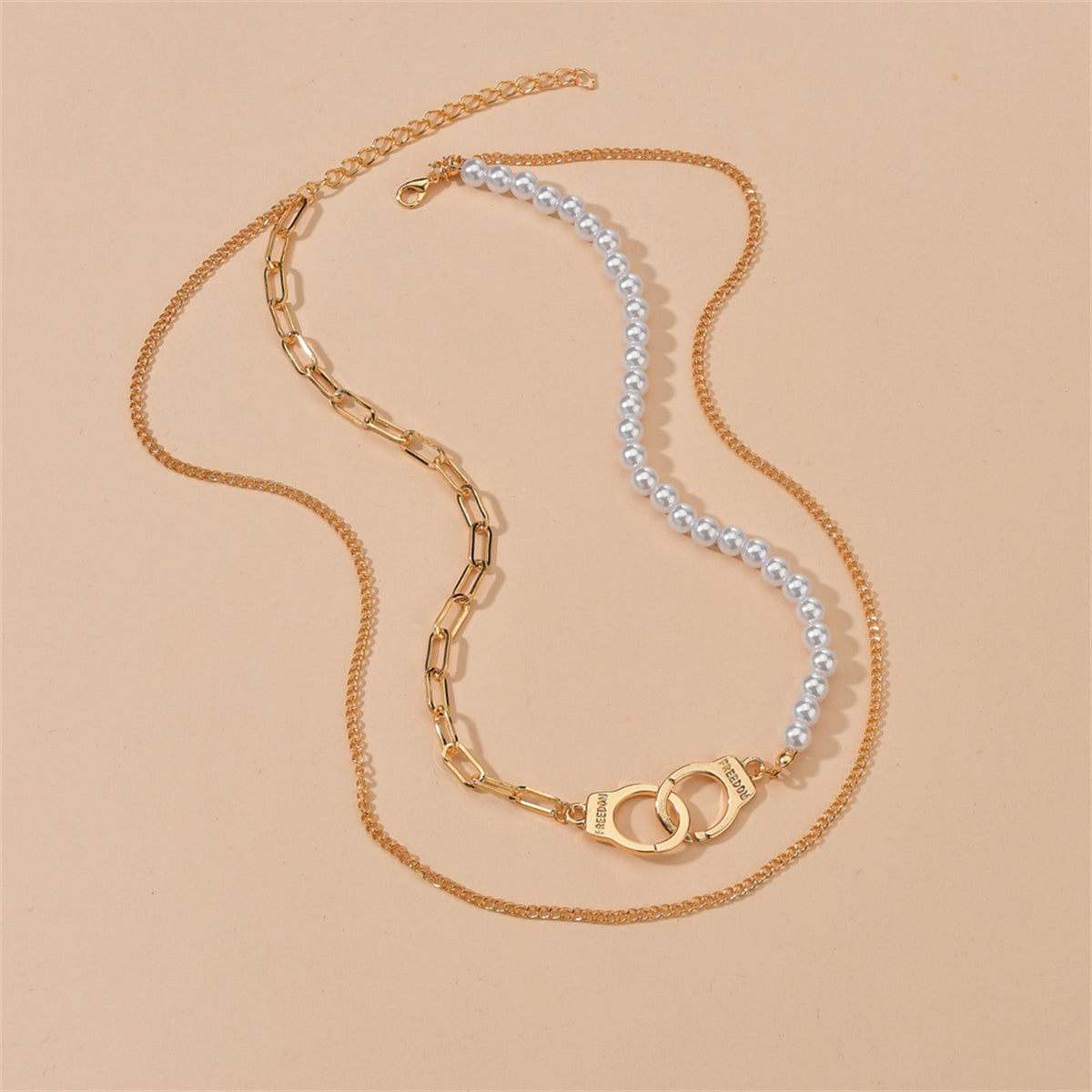 Two necklaces displayed together: a pearl necklace and a gold chain with a stylish 18K gold-plated handcuff pendant.