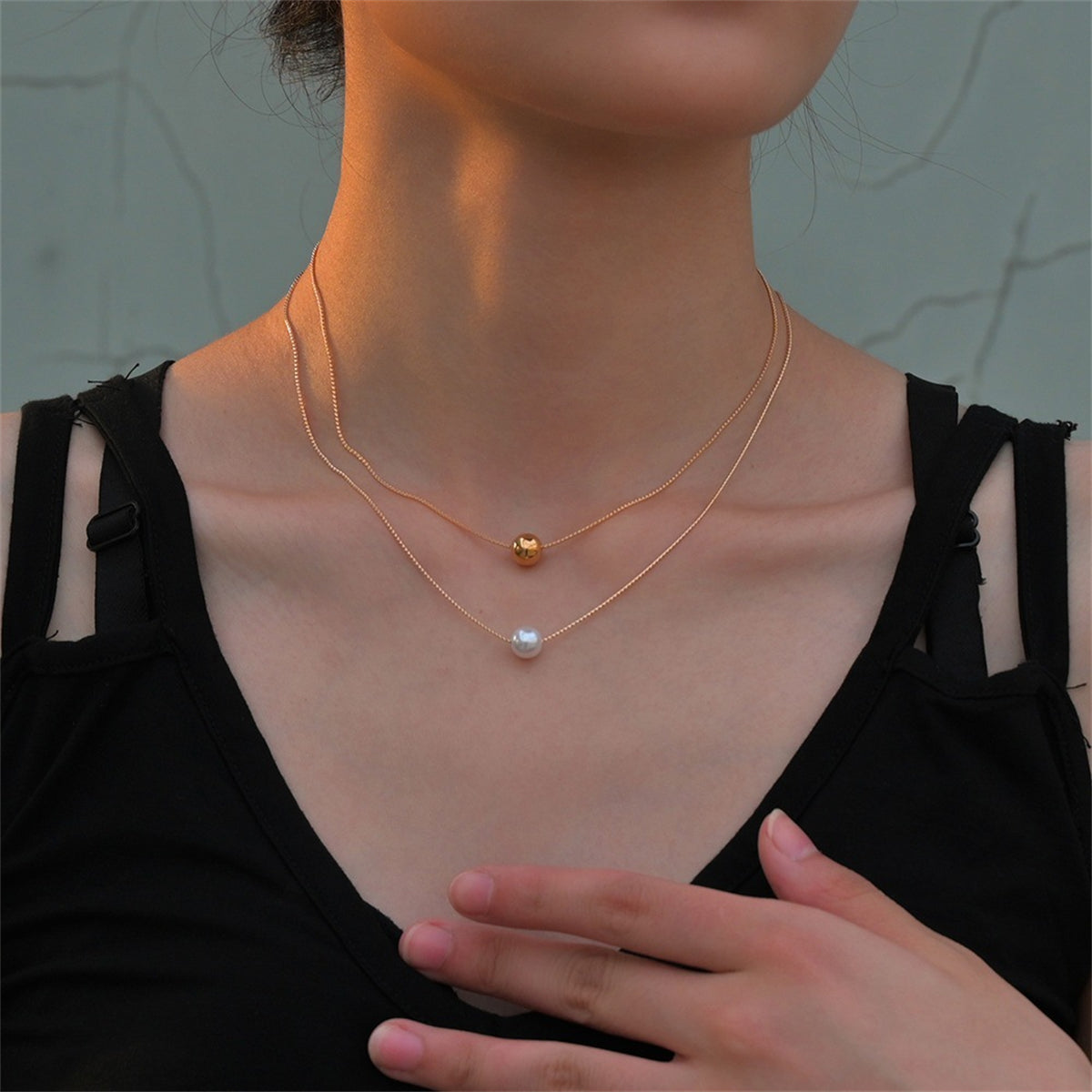A layered necklace featuring two gold and white pearls, complemented by 18K gold-plated beads.