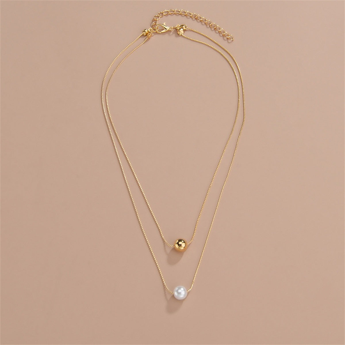 Elegant layered necklace showcasing two gold and white pearls, adorned with 18K gold-plated beads.