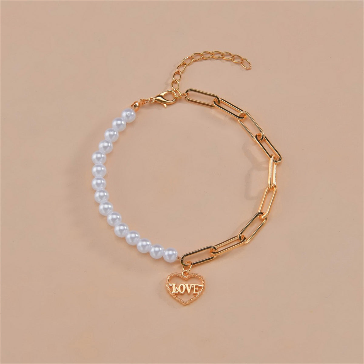 White pearl bracelet with a gold heart charm, showcasing a blend of classic elegance and heartfelt sentiment.