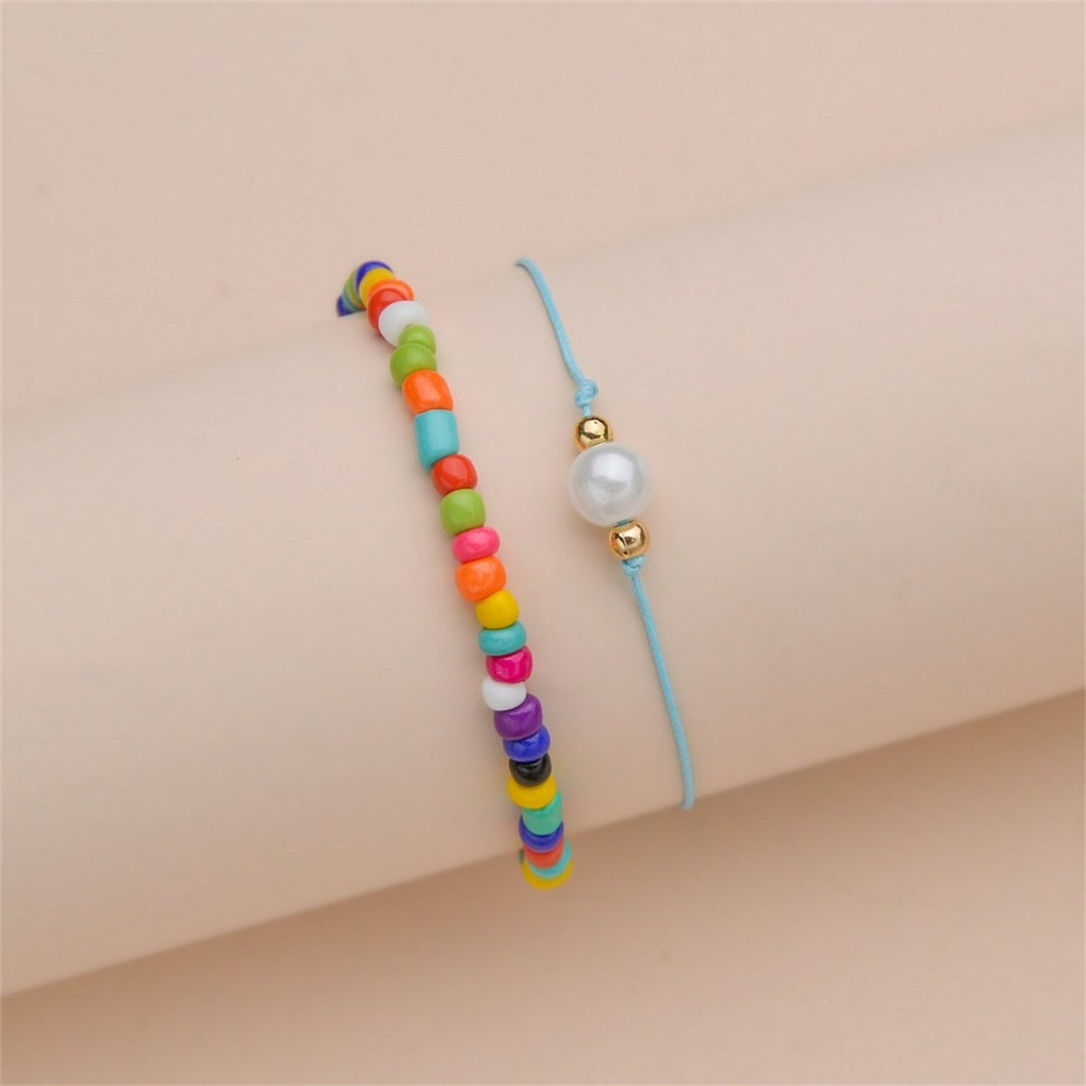 Two anklets with rainbow beads and a blue cord, representing the Red Multicolor Howlite Stretch Anklet Set.