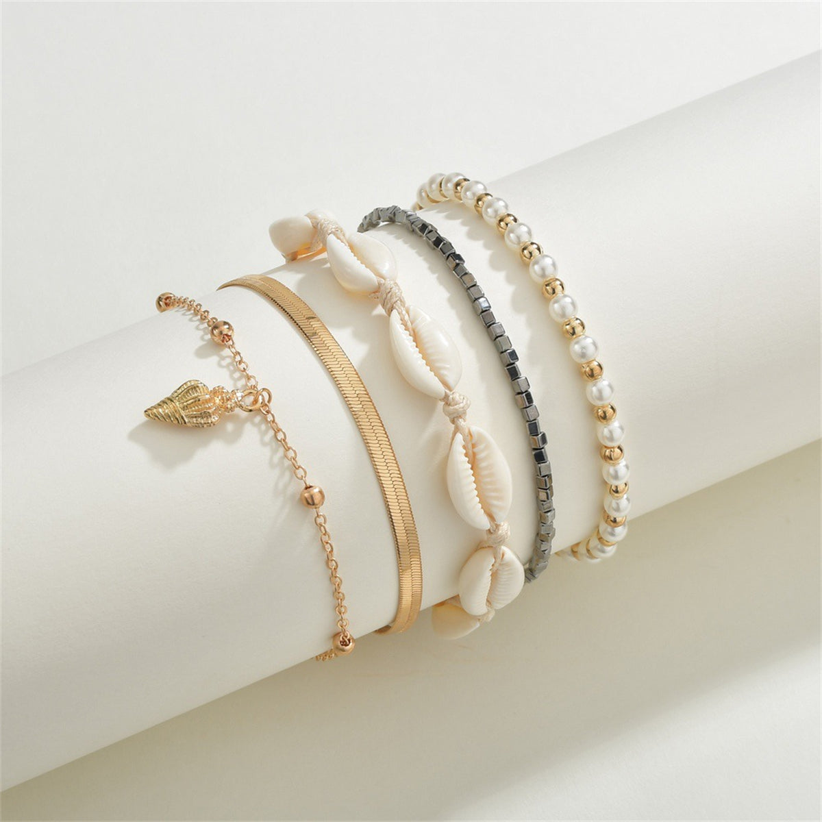 A set of three gold and black anklets featuring shells and pearls, highlighting the exquisite 18K gold-plated craftsmanship.