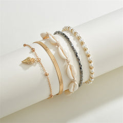 A set of three gold and black anklets featuring shells and pearls, highlighting the exquisite 18K gold-plated craftsmanship.