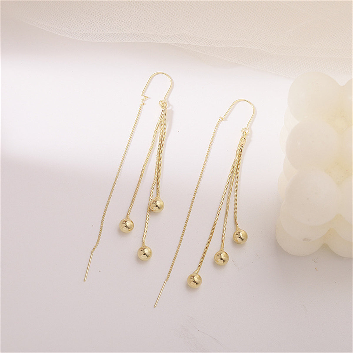 Chic 18K gold-plated threader earrings adorned with two beautiful beaded balls, ideal for a fashionable statement.