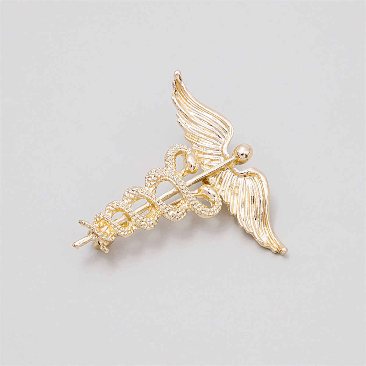 Exquisite gold caduceus brooch adorned with angel wings and a snake, embodying the spirit of healing and medical professionalism.