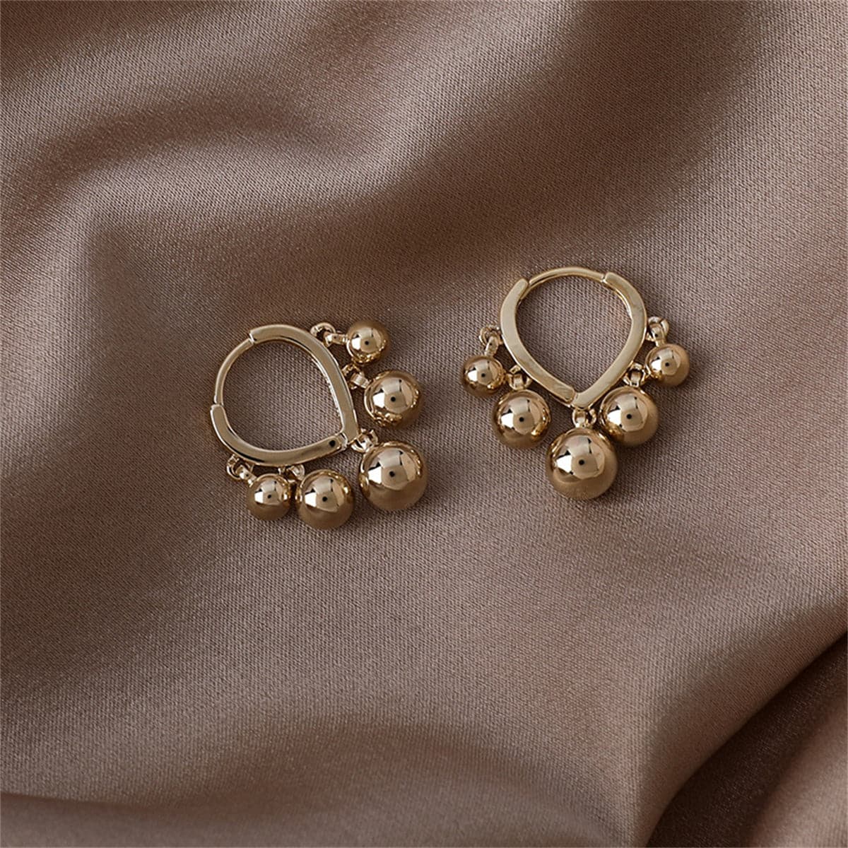 Elegant 18K gold-plated hoop earrings featuring ball tassels for a chic and stylish look. Perfect for any occasion.
