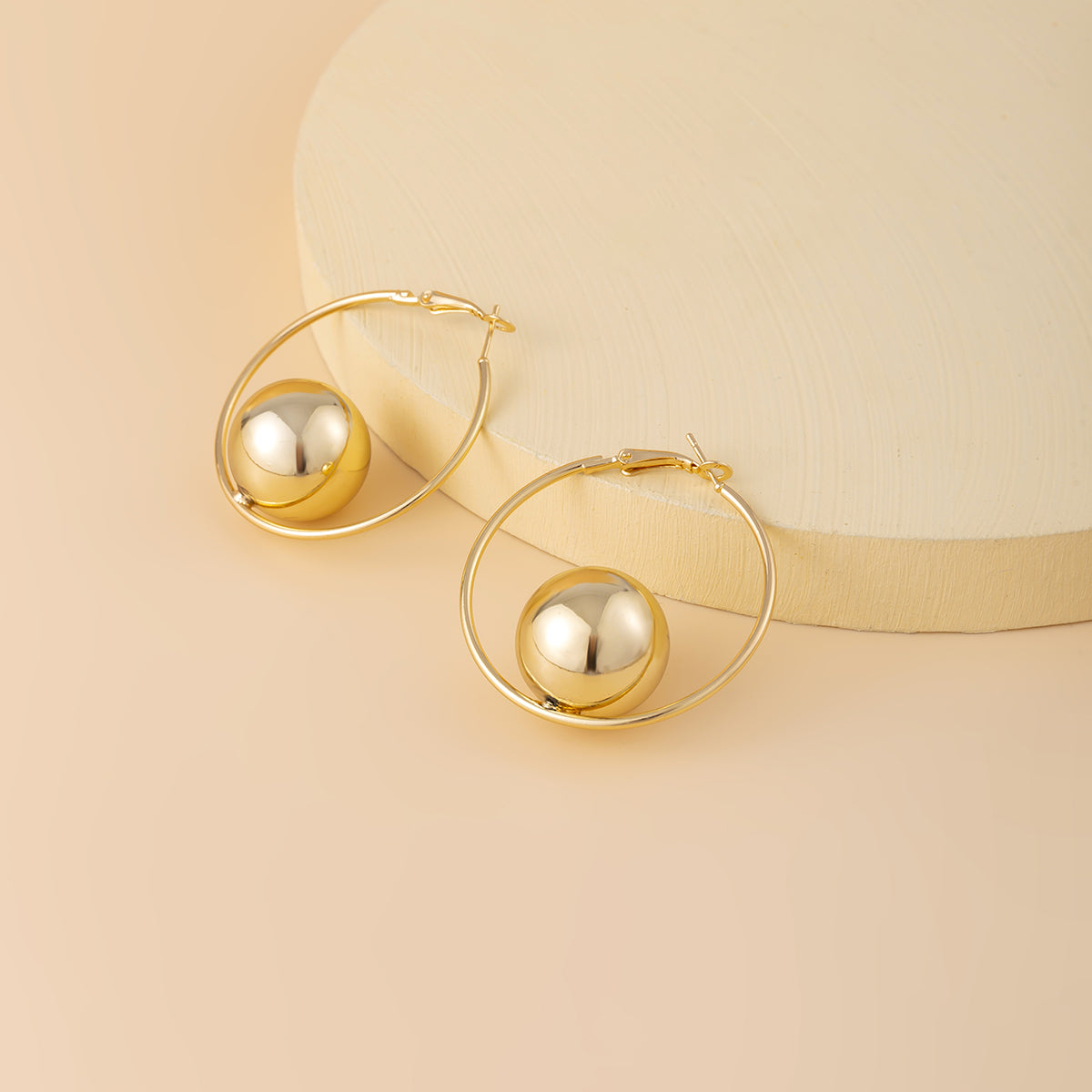 Trendy 18K gold-plated hoop earrings featuring a delicate ball at the end, a must-have accessory for any fashionista.
